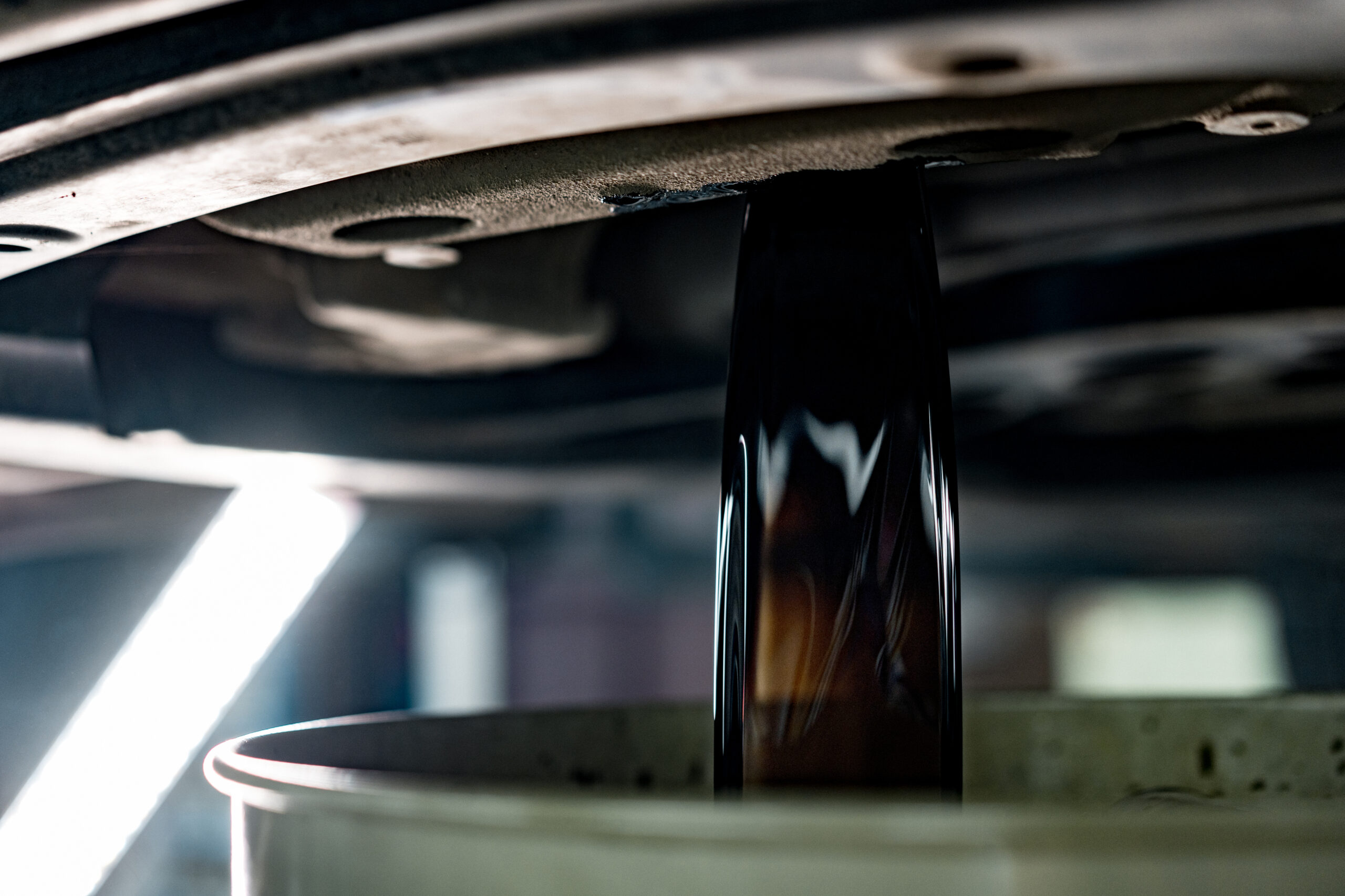 Old dirty oil pouring from the car engine in car service station close up photo